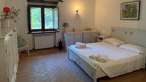 A bedroom with a bed, bedside tables, a radiator, a window, and a chair. - Villa on the Sea with pool and direct descent to the beach (Parghelia (Tropea))