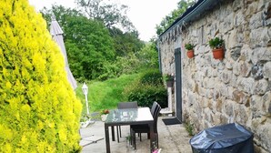 Eine Terrasse mit Tisch und Stühlen, ein überdachter Sitzbereich und eine Steinsäule.