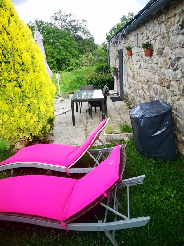 Un patio con mesa y sillas, una zona de estar cubierta y una pared de piedra.