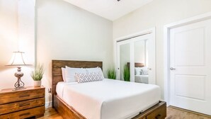 Un dormitorio con una cama de madera, una mesita de noche con lámpara y un armario.