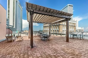 Eine Dachterrasse mit einer Pergola, Tischen und Stühlen mit Blick auf eine Stadtlandschaft und historische Gebäude.