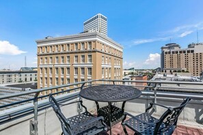 Un balcón con una mesa redonda y dos sillas, con vistas a un paisaje urbano con edificios históricos.