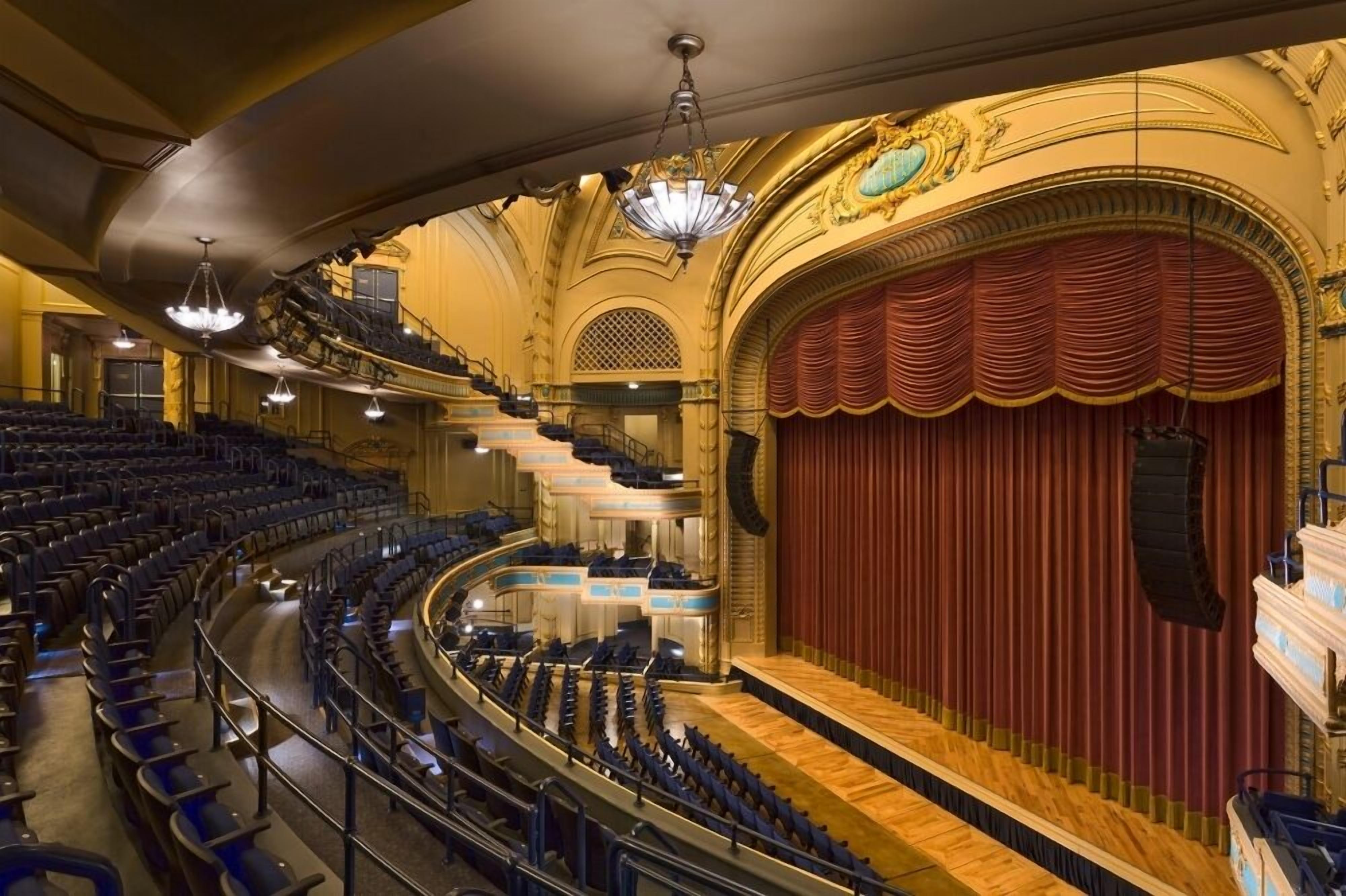 Een theater met een groot podium, meerdere balkons en versierde architectuur.