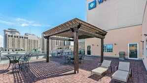 Un patio en la azotea con mobiliario exterior, una pérgola y vistas panorámicas de la ciudad.
