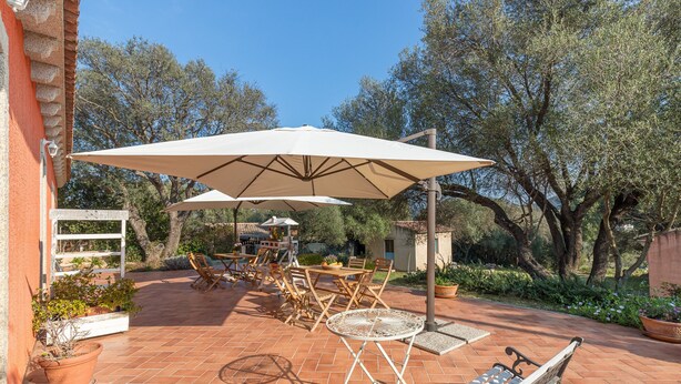 Une terrasse extérieure avec un sol en terre cuite, une table ronde et un banc.