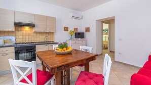 Une cuisine moderne avec des meubles en bois, une table à manger avec des coussins rouges et un téléviseur fixé au mur.