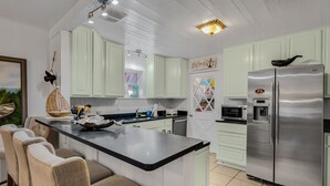 Een moderne keuken met een centraal eiland, witte kasten, roestvrijstalen apparatuur en een eetgedeelte met comfortabele stoelen.