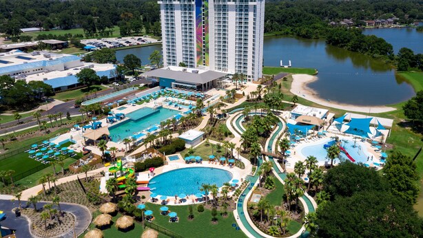 A resort with multiple swimming pools, a large hotel building, and a lake. - Lakeside Daze! (Montgomery)