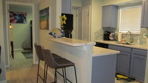 A modern kitchen with a central island, bar stools, and a dining area. - Lakeside Daze! (Montgomery)