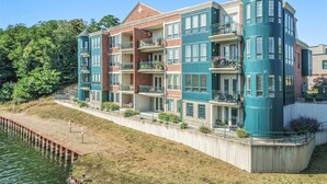 A multi-story building with balconies, a waterfront view, and a brick facade. - Cozy Efficiency at Downtown Manistee (Manistee)