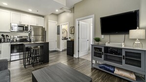 A modern kitchen with white cabinets, stainless steel appliances, and a bar area. - Cozy Efficiency at Downtown Manistee (Manistee)