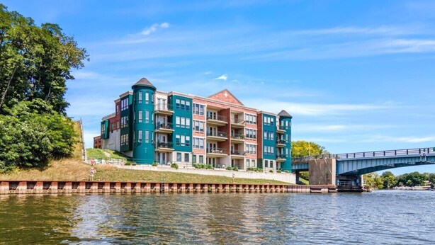 A multi-story hotel with balconies, located near a body of water with a bridge in the background. - Cozy Efficiency at Downtown Manistee (Manistee)