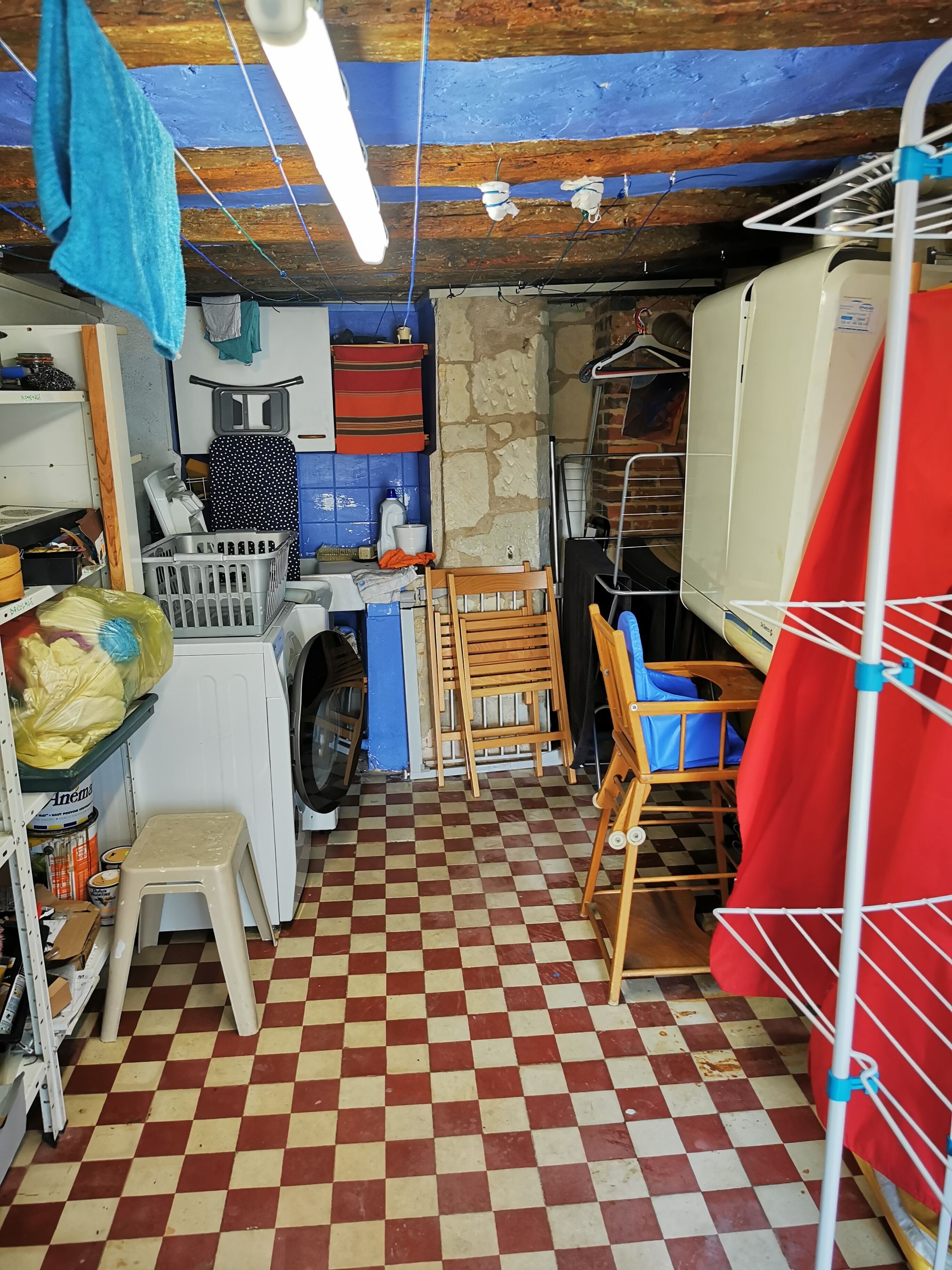 A laundry room with a washing machine, drying rack, and ironing board.