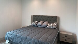 Un dormitorio con una cama grande, un cabecero capitonado y dos mesitas de noche con cajones.
