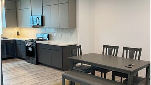 Una cocina moderna con gabinetes grises, horno integrado y un comedor con mesa y sillas.