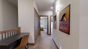 Un corridoio con zona pranzo, caratterizzata da una panca e un tavolo in legno, pavimento rivestito di moquette e parete decorata con quadri.