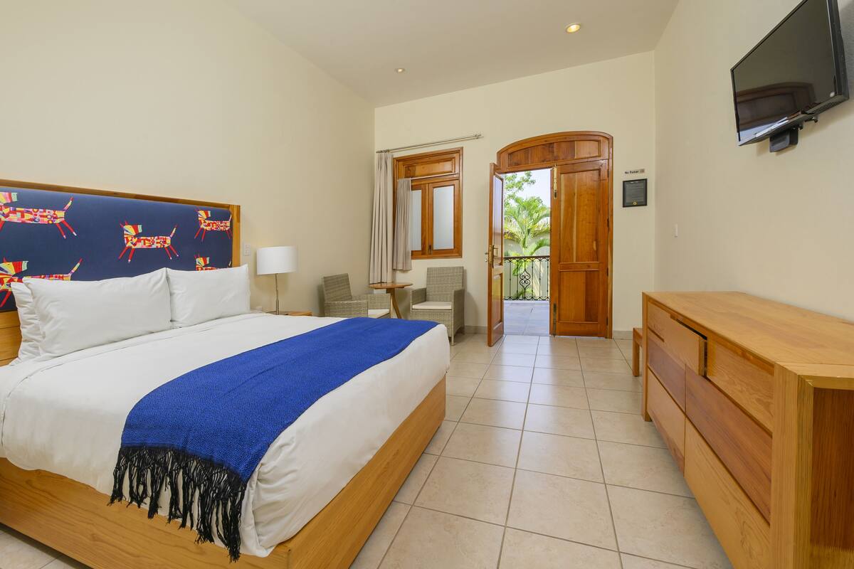 Une chambre avec un lit, une télévision, une commode en bois et une vue sur l’extérieur.