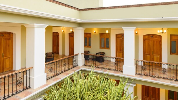 A spacious atrium with a large central plant, multiple balconies, and wooden doors. - XTILU Hotel - Adults only (Oaxaca)
