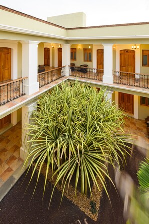 A spacious atrium with a large central plant, multiple balconies, and wooden doors. - XTILU Hotel - Adults only (Oaxaca)