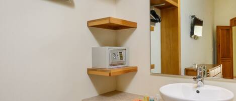 A bathroom with a white sink, wooden shelves, a mirror, and a radio.