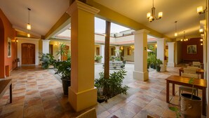 A spacious indoor area with tiled flooring, multiple seating arrangements, and potted plants. - XTILU Hotel - Adults only (Oaxaca)