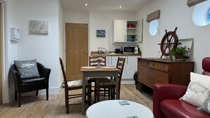 Un espacio habitable compacto con comedor, cocina y un sofá rojo.
