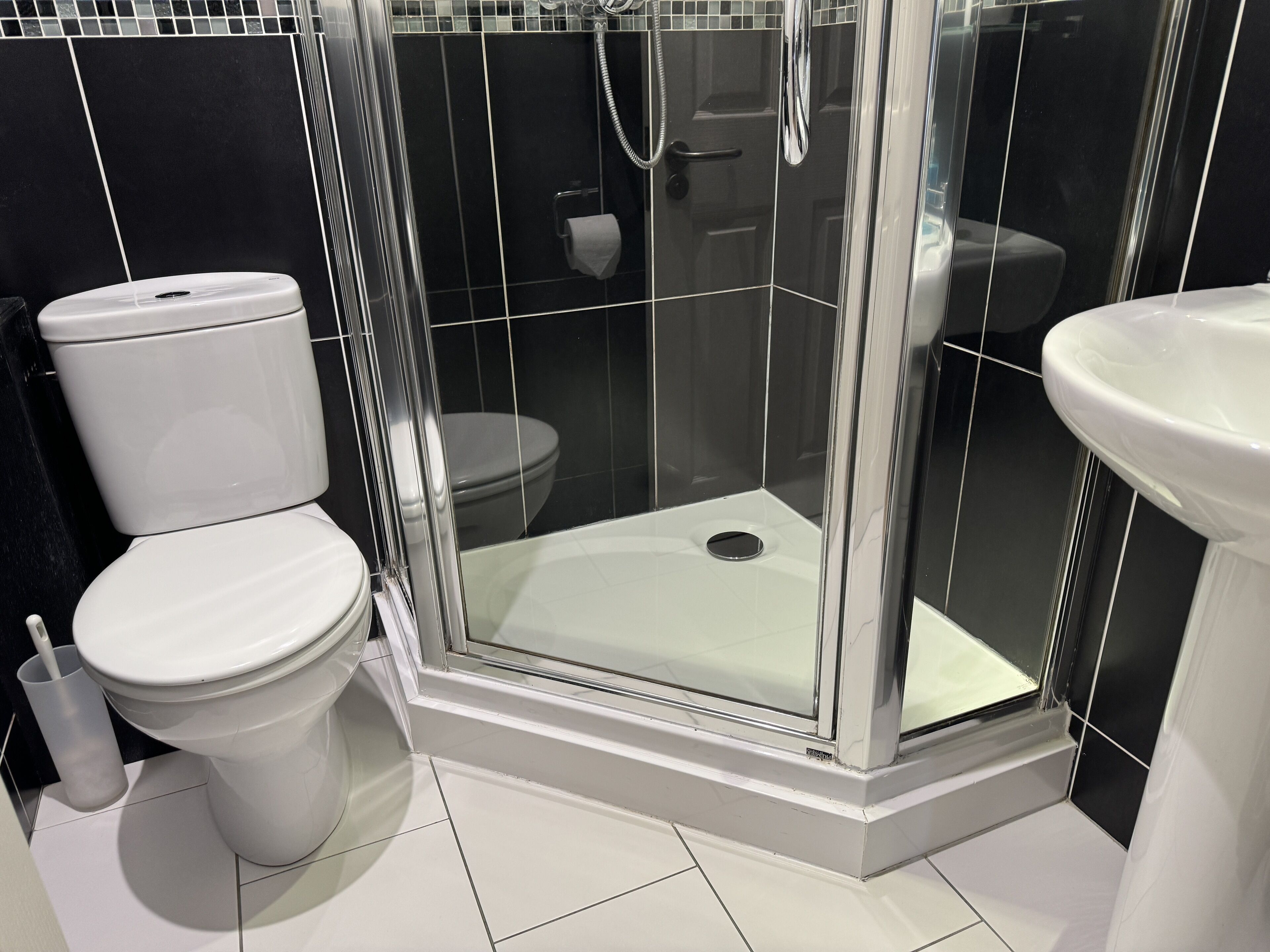 A modern bathroom with a glass-enclosed shower, a toilet, and a sink.