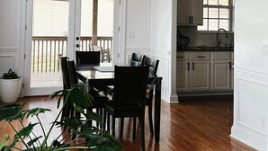 A dining area with a wooden table and chairs, a chandelier, and a view of the backyard through a glass door.
