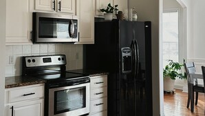 A kitchen with white cabinetry, stainless steel appliances, and a wooden floor.