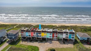 A row of colorful beachside buildings with a view of the ocean. - Beachfront condo w Sunrise and Sunset Views (Surfside Beach)