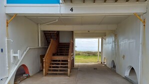 A covered outdoor area with a wooden staircase leading to a higher level. - Beachfront condo w Sunrise and Sunset Views (Surfside Beach)