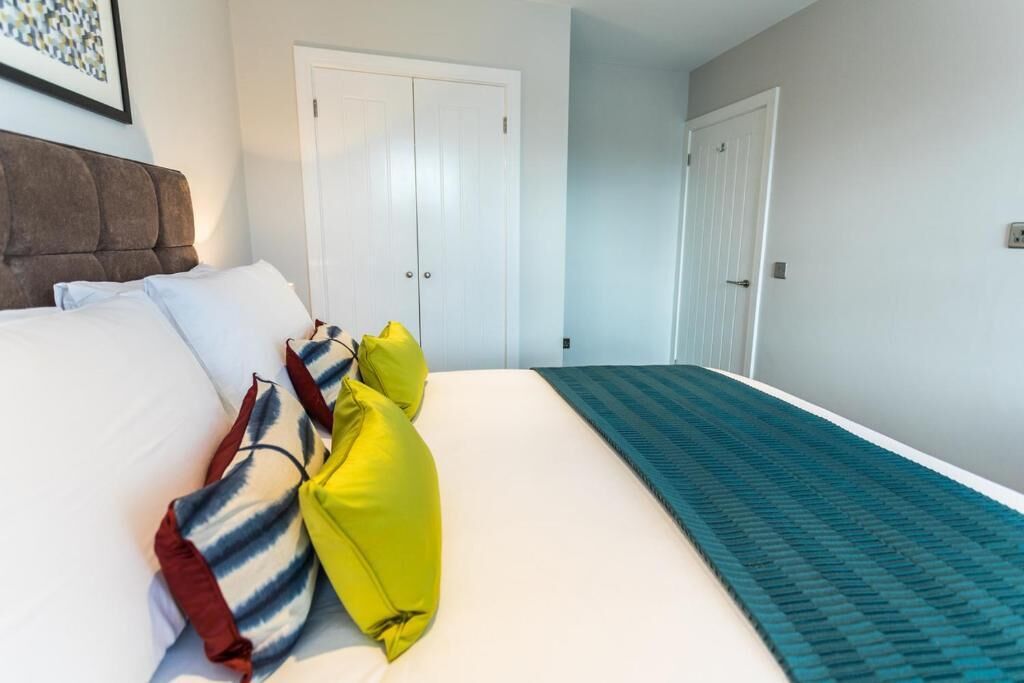A bedroom with a bed, pillows, a headboard, and two doors.