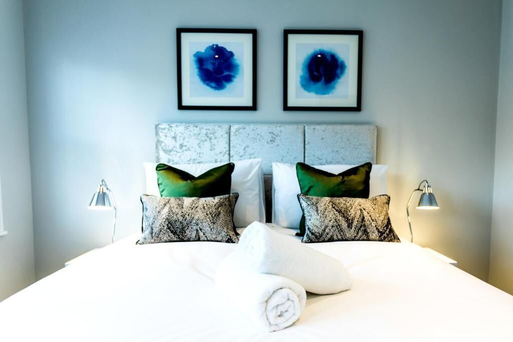 Habitación de hotel con una cama grande, dos cuadros abstractos enmarcados y un cabecero moderno.