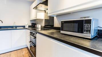 A modern kitchen with white cabinets, a black countertop, and a built-in microwave.