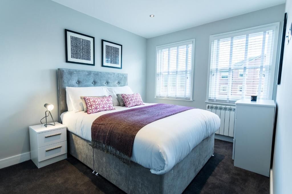 A bedroom with a bed, nightstand, and two framed pictures on the wall.