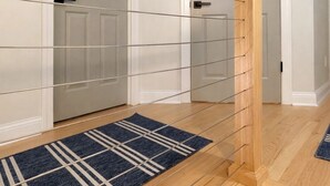 Una escalera con barandilla de madera y un tapete azul estampado al final.