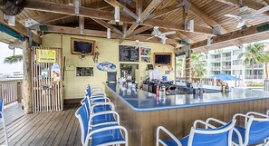 A bar area with a counter, blue chairs, and a wooden ceiling.