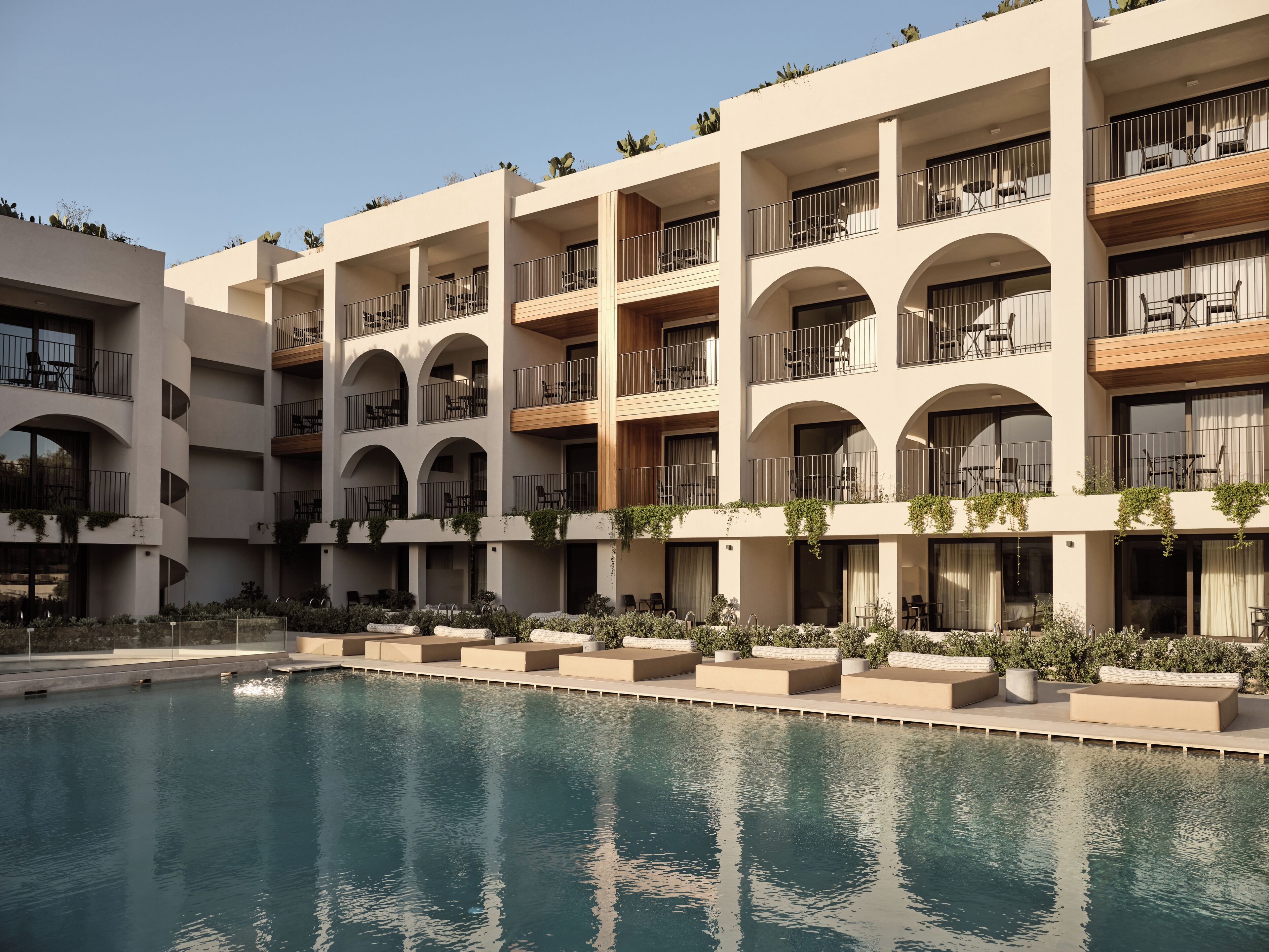 A hotel with multiple balconies, outdoor seating, and a swimming pool.