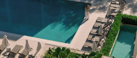 Un área de piscina en la azotea con múltiples sillas de descanso y una piscina pequeña.