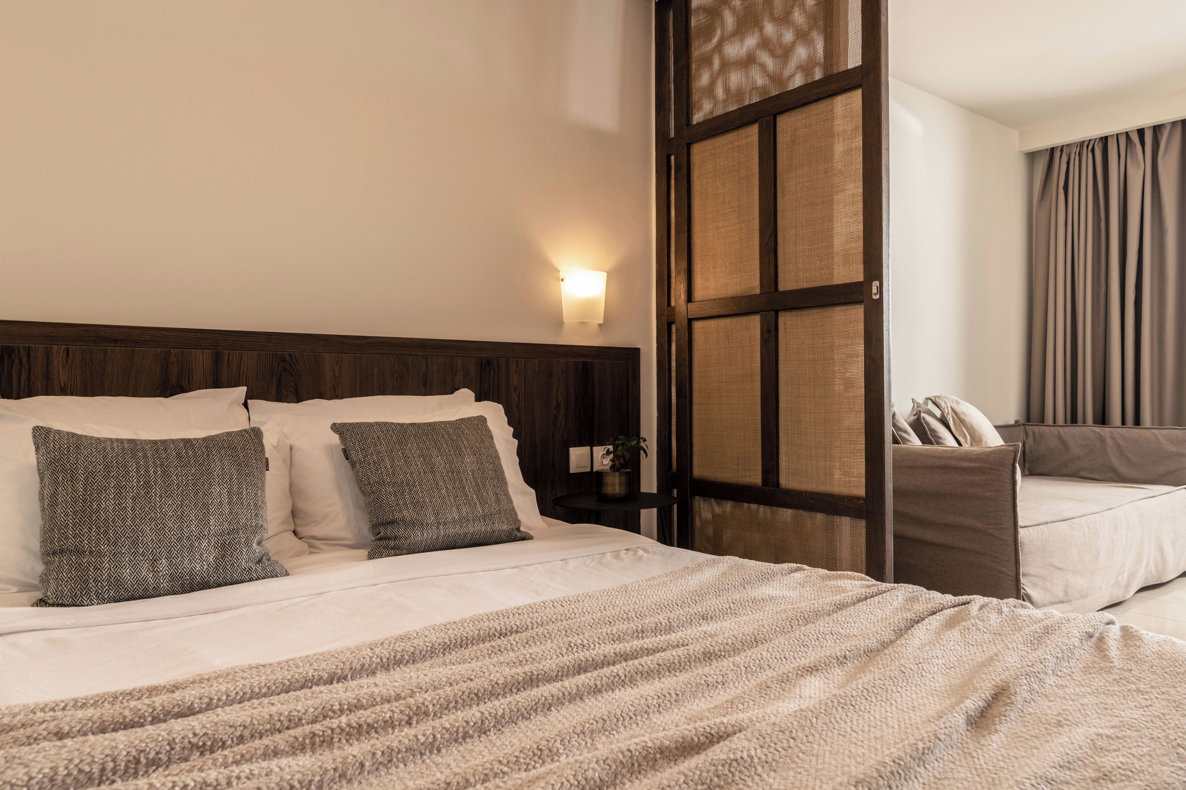 Une chambre d’hôtel avec un lit, une table de chevet, une lampe fixée au mur et une vue sur l’extérieur.