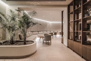 Un interior moderno con una zona de estar curva, una estantería de madera y una planta en maceta.