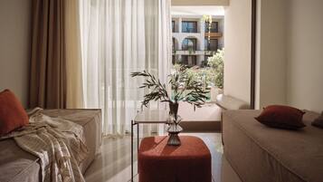 Habitación de hotel con dos camas, una planta en maceta y vista a un patio.