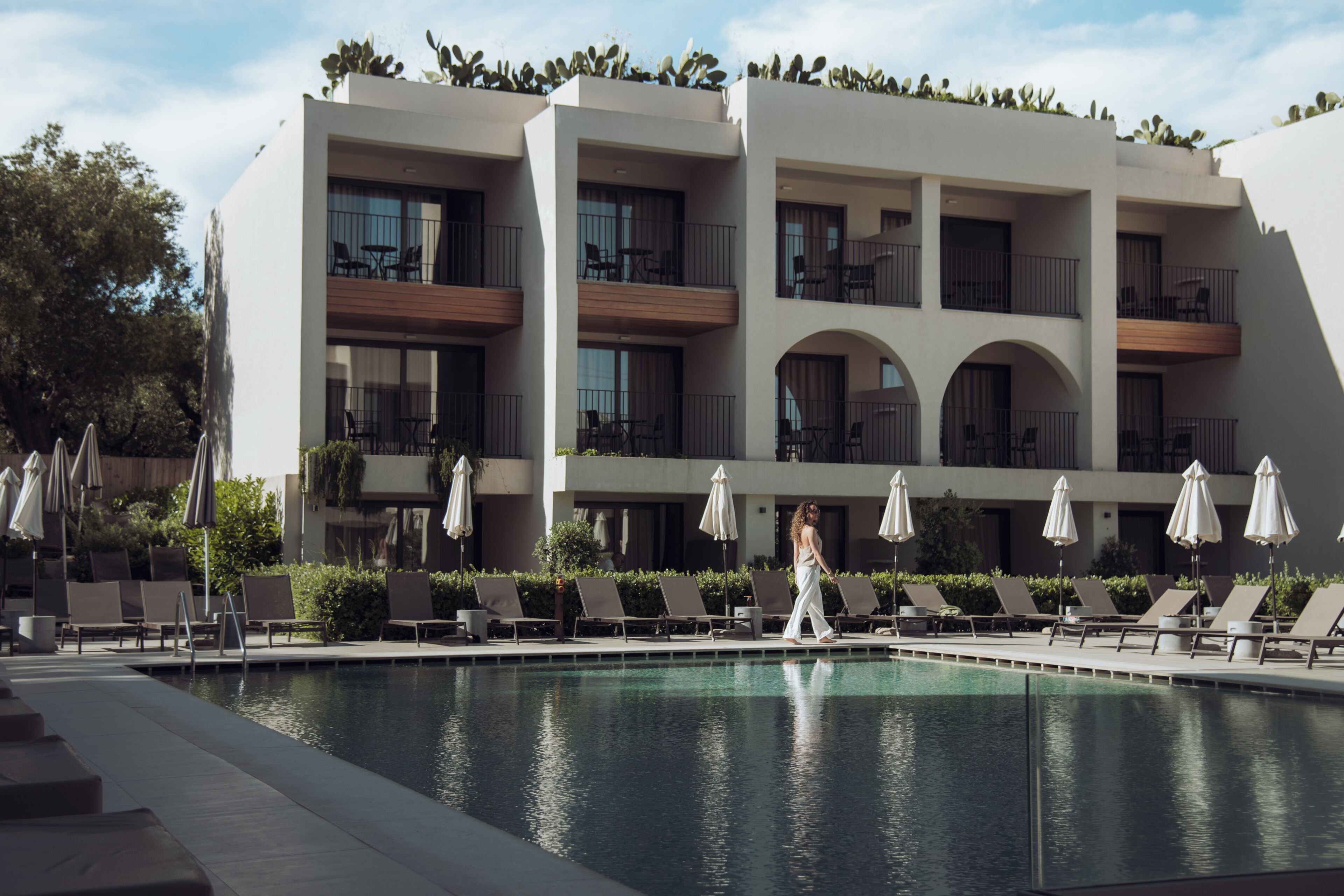 A modern hotel with a pool area, multiple balconies, and outdoor seating.