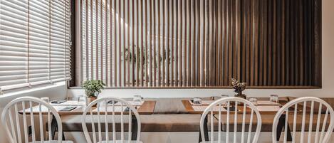 A dining area with a long table, four white chairs, and a bench.