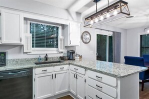 Una cocina moderna con armarios blancos, encimera de granito y lavavajillas empotrado.