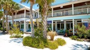 A beachfront hotel with multiple balconies, outdoor seating, and a sign for Olive Oil Outpost. - Beautiful 3 bdrm Private home with HEATED pool 5 mi from Anna Maria Island!! (Bradenton)