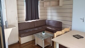 A compact living space with a sofa, a small table, and a chair. - Your vacation with peace of mind! (Agde)