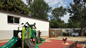 A playground with a slide, climbing structures, and a bench. - Your vacation with peace of mind! (Agde)