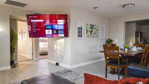 Un soggiorno moderno con una televisione a schermo piatto montata a parete che mostra diverse piattaforme di streaming.
