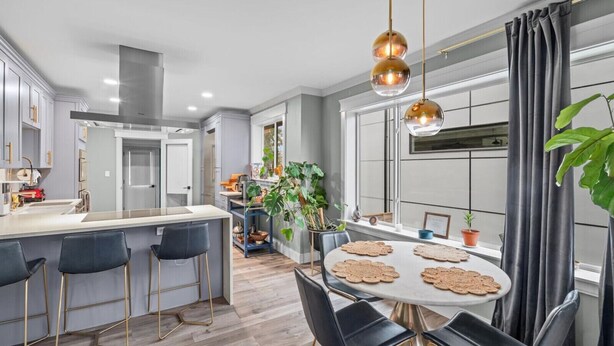A modern kitchen with a central island, bar stools, a dining table with placemats, and pendant lighting. - Casa Ballard - Entire Renovated Home with Patio, Deck & Private Basement (Seattle)